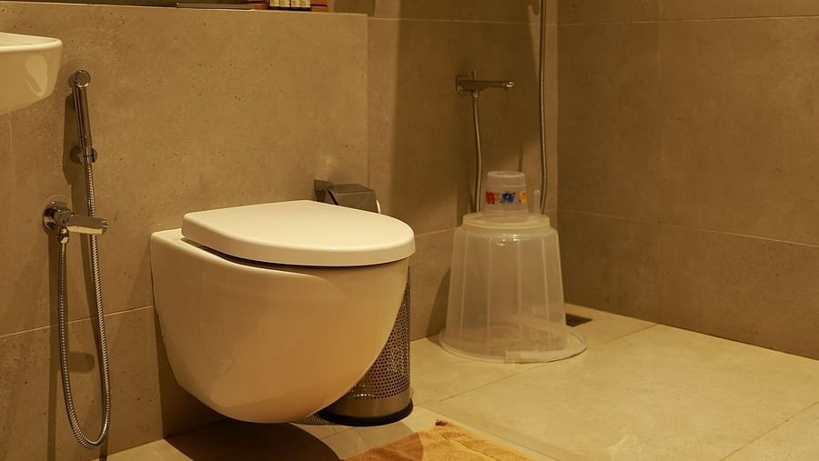 A contemporary bathroom at Vaasta Vagamon featuring a wall-mounted toilet, a walk-in shower with a rainfall showerhead, and a bath mat.