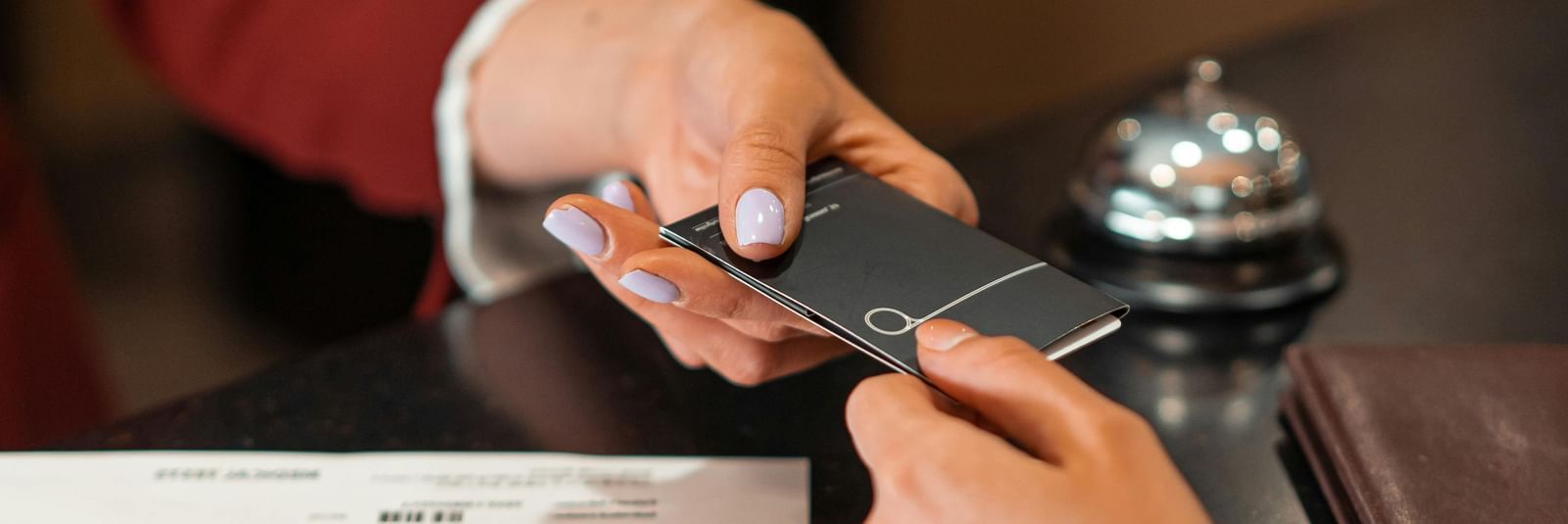 The receptionist handing over the key card to a guest over the front desk.