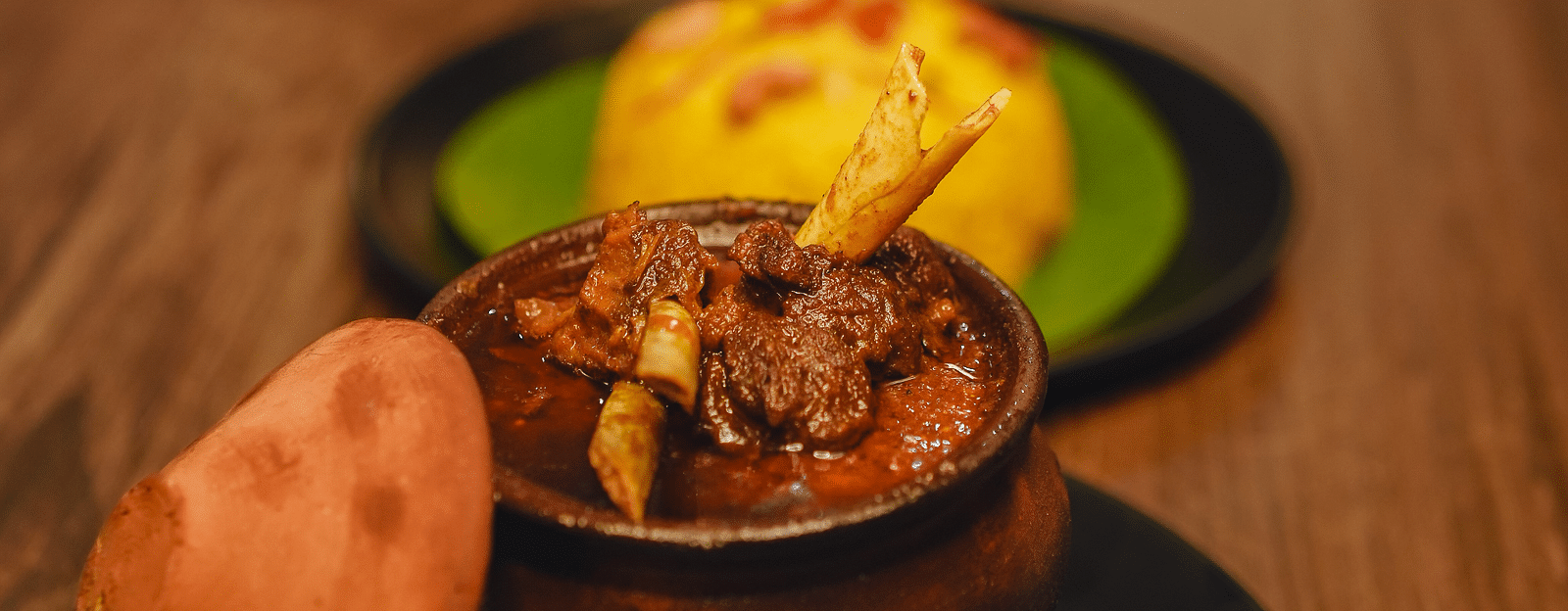 image featuring a mutton preparation served in an earthen pot with yellow rice - Dip Holidays, Birbhum