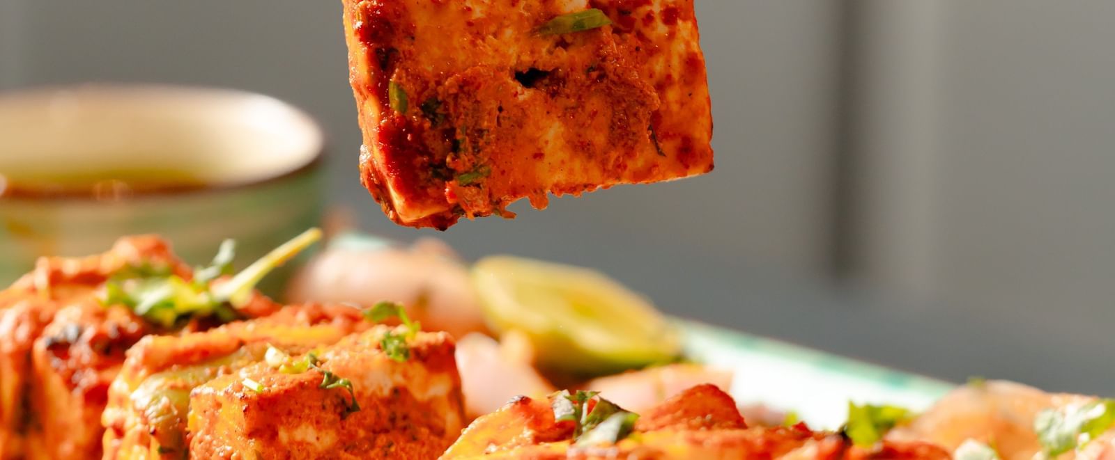 Fork lifting a piece of paneer tikka from a platter of grilled items | Pravasa Hotel, Vijayapura