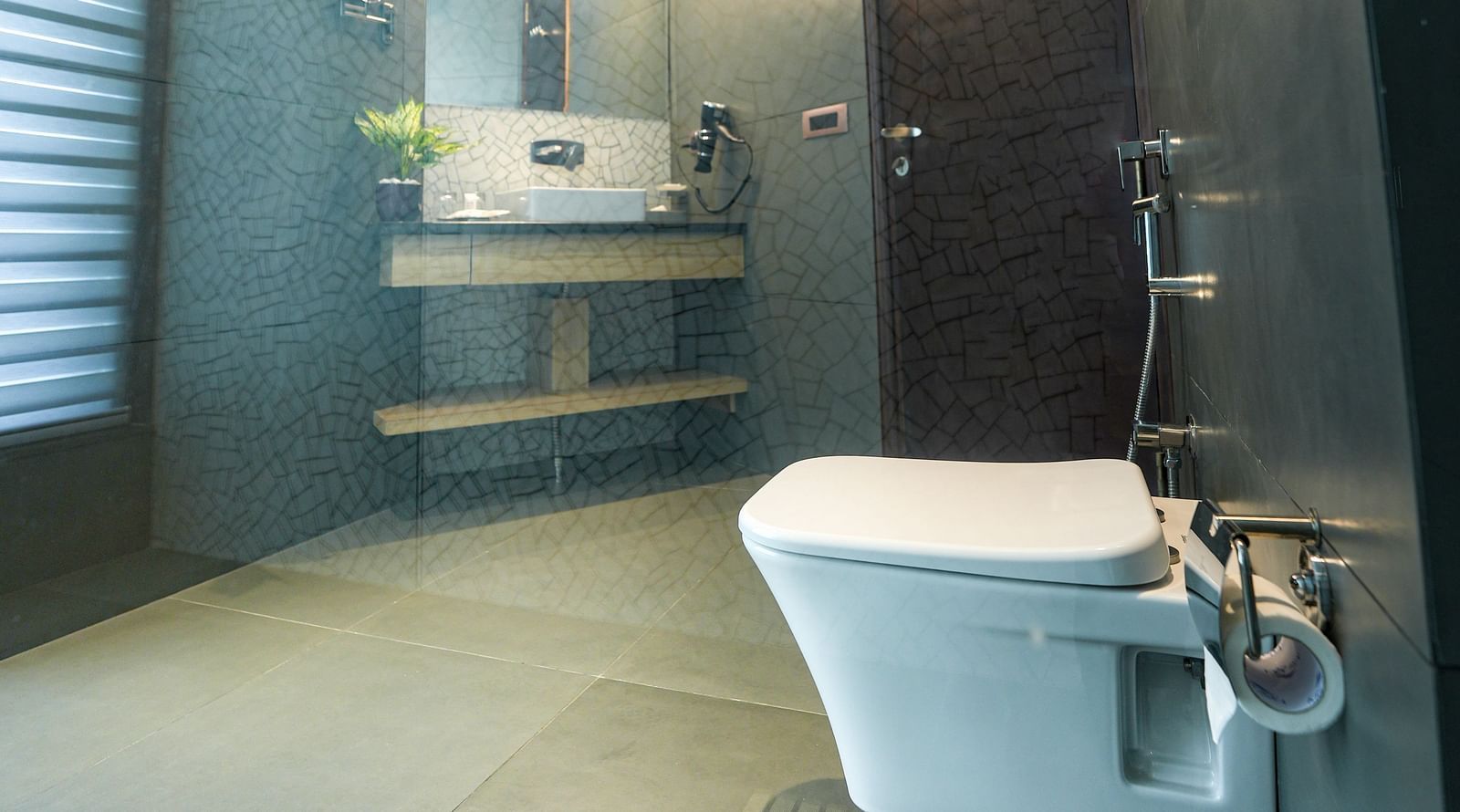 An brightly lit washroom of our suite in Bankhandi with a commode, a large sink and wall-mounted mirror - NAMAMI BY ZENQ BANKHANDI