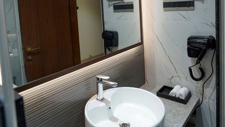 A modern bathroom featuring a neat vanity area along with a back-lit mirror at M2 Square by Monday Premium.
