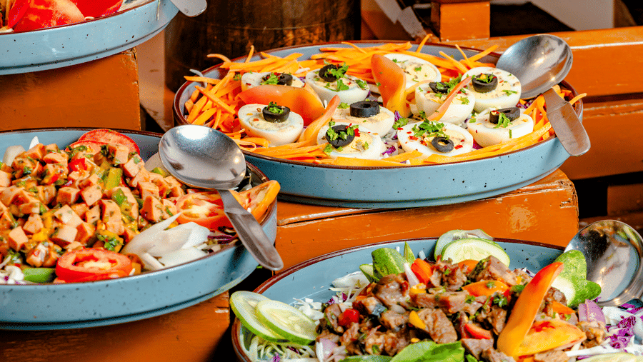 A selection of fresh salads and appetisers served at Marble Arch, part of the Noor-Us-Sabah Palace, Bhopal, displayed in blue bowls on a wooden buffet.