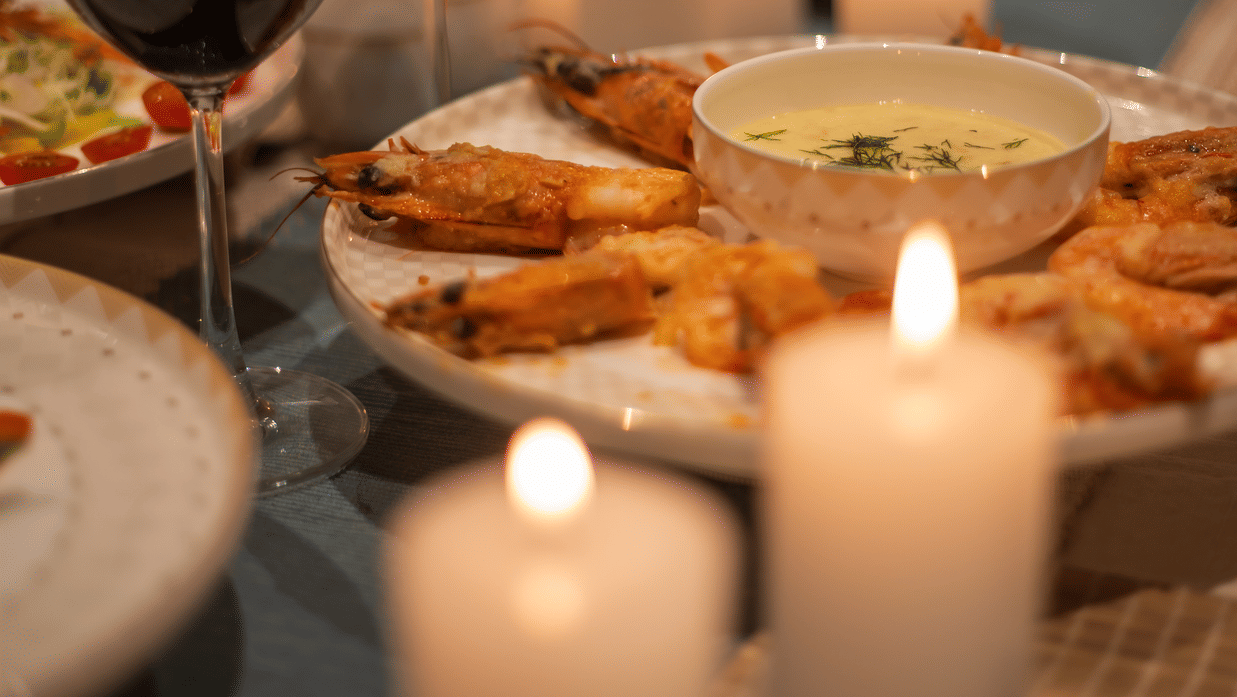 A dining table setup with wine glasses, appetisers, and lit candles - Lamrin Morjim Goa