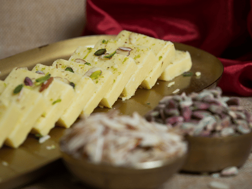 Traditional Bengali Sandesh sweets cut into pieces and beautifully arranged on a decorative plate.