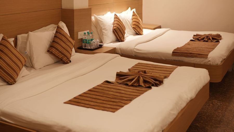 A cosy bedroom at Amer Greens, Bhopal with two single beds, neutral decor, and soft lighting.
