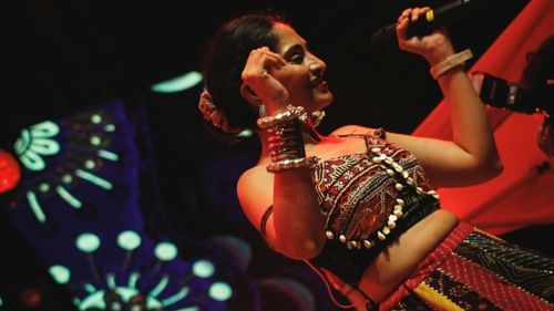 Close-up of a female singer on stage with decorative lighting in the background.
