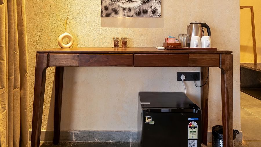 An image of a table where tea and coffee maker is placed along with some cups, and glasses and below it there is a min fridge - Kurja Jawai