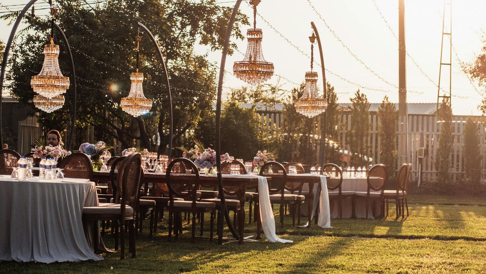 a lush green lawn with decorative strings hanging from the tall pillars as decoration on a bright sunny day
