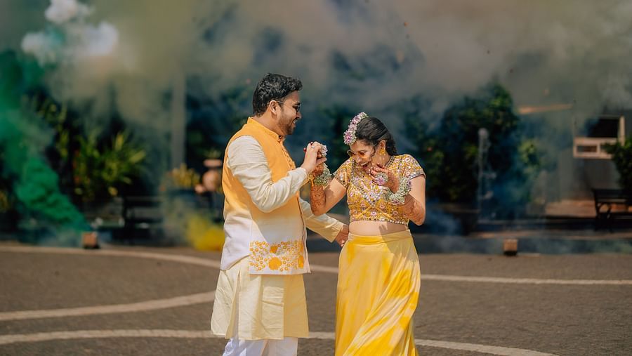image of the couple standing close to each other at darza resorts with colour bombs exploding in the background