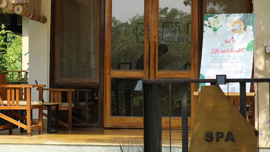Entrance to the spa at Saraca Resort & Spa Corbett with large glass doors with wooden panels and greenery surrounding the building
