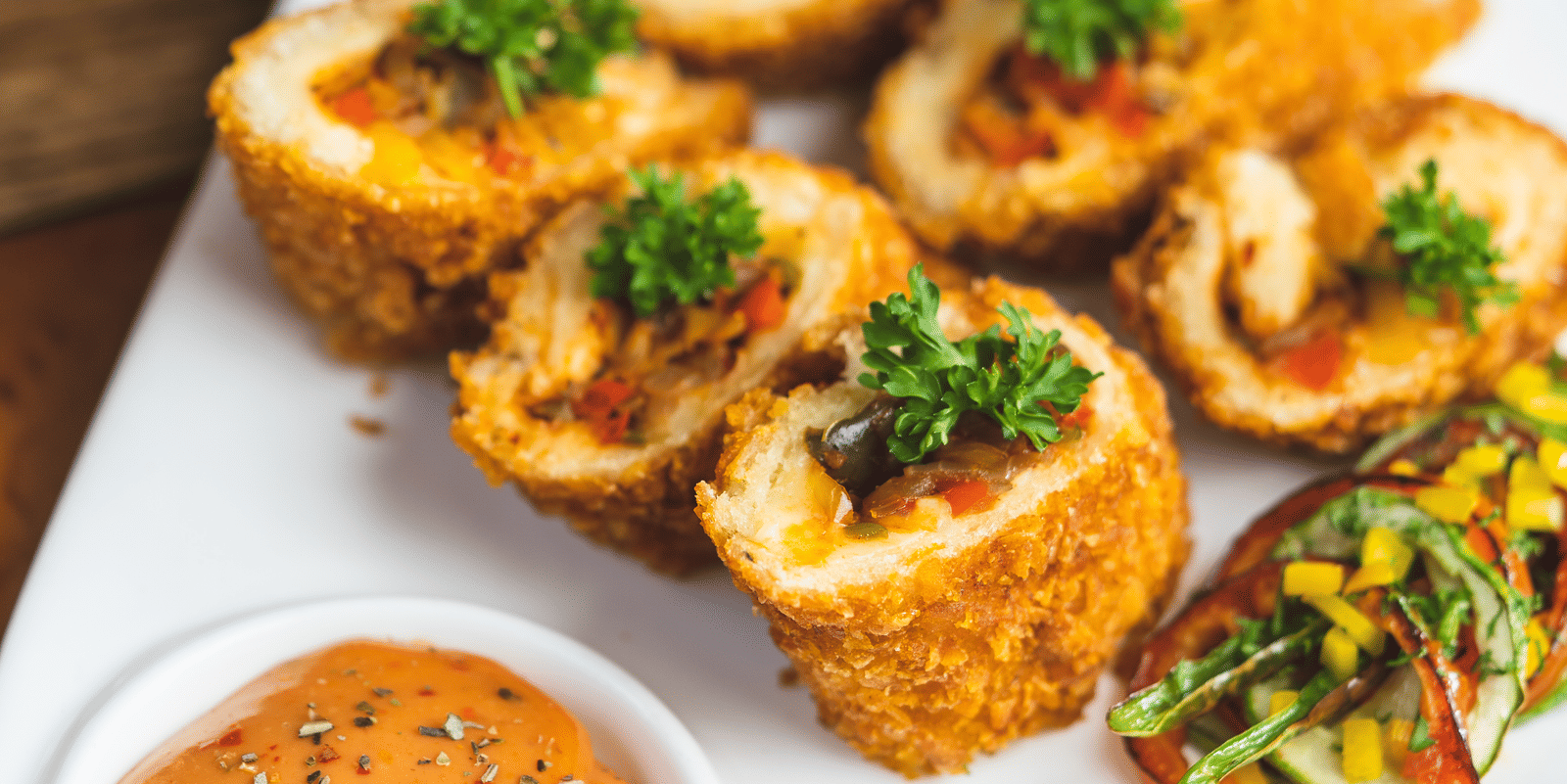 Close-up of an appetiser dish—fried rolls or snacks—served with a tangy dipping sauce on a white platter at Hotel Hukam's Lalit Mahal.