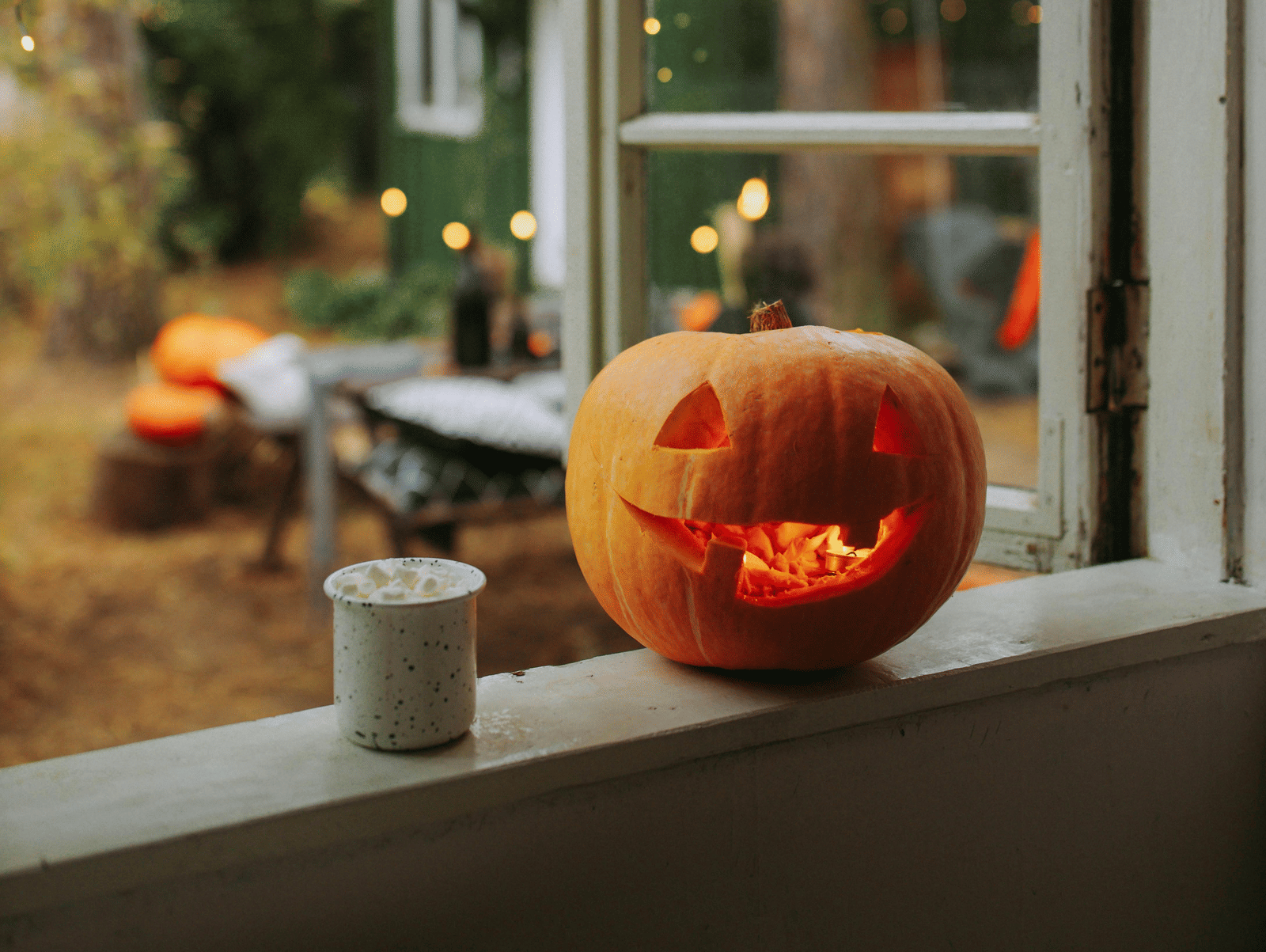 Pumpkin with a carved face placed on a window sill, glowing in the warm afternoon light.