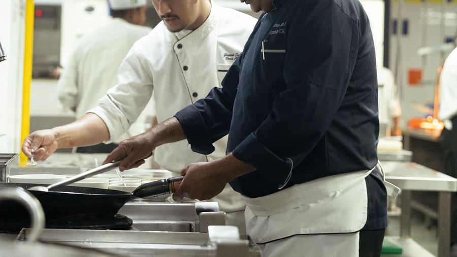 Two chef working togetehr in a kitchen at Lounge area with four seater outside a bedroom at Ananta Spa and Resort, Ajabgarh