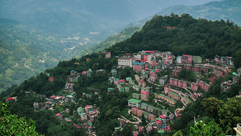Aerial view of Gangtok featuring multiple buildings on the mountain slopes under a clear sky