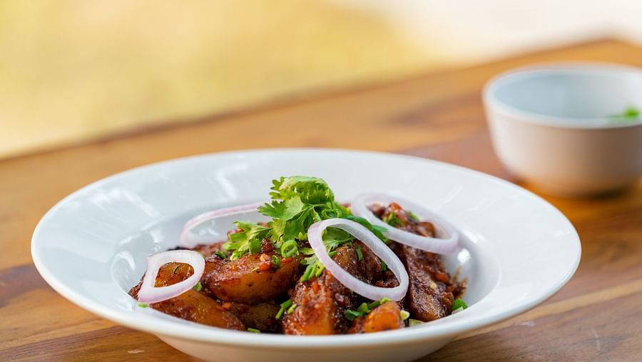 image of a person garnishing the dish with finely chopped coriander at the kalptaru restaurant in aranya vilas  