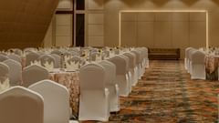 A view of the speaker table from the audience end in a party hall in ajmer featuring warm lighting and carpeted floors - Sarovar Portico, Ajmer