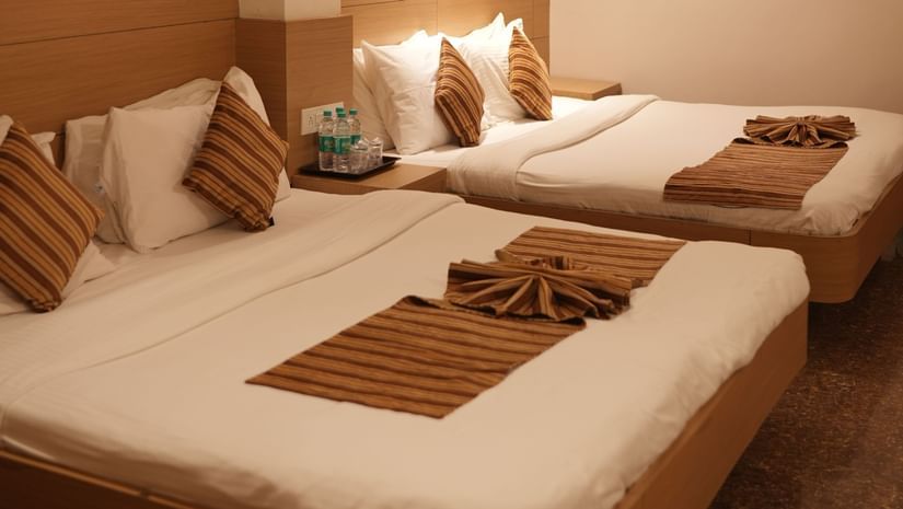 A cosy bedroom at Amer Greens, Bhopal with two single beds, neutral decor, and soft lighting.