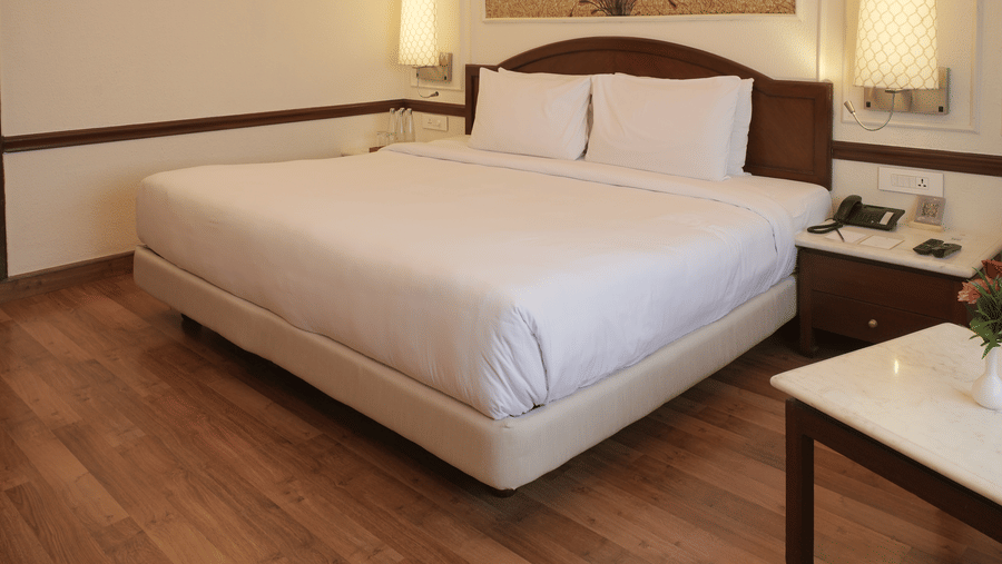The Superior King bedroom at Clarks Amer, Jaipur includes a large bed, hardwood floors, and a decorative ceiling light fixture.