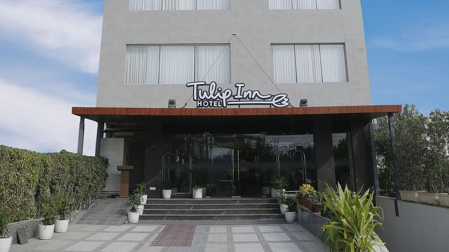 An image of our hotel building with the name of the hotel attached on the signboard and a blue sky in the background - Tulip Inn, Zirakpur