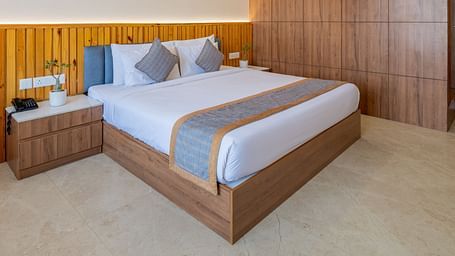 Deluxe room with wooden interiors, a king size bed, and a ceiling fan at Hotel Highway King, Bagru