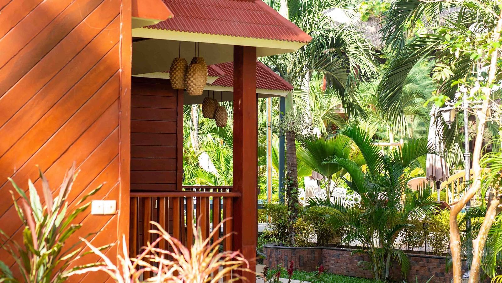 A red building with two levels with greenery around and trees in the background - Coral Reef Resort & Spa, Havelock