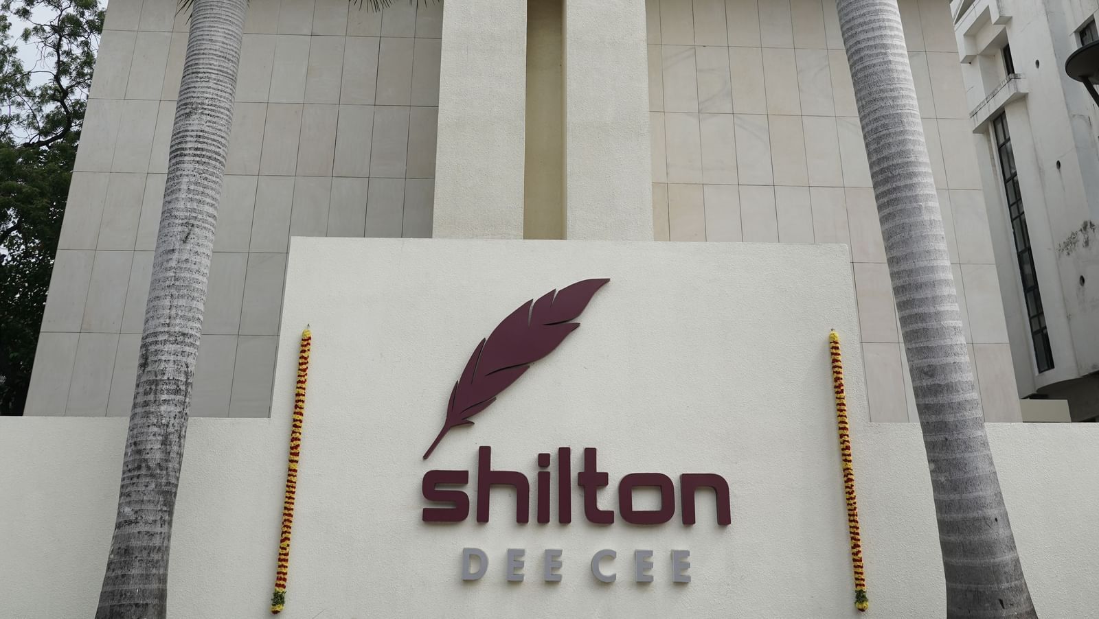 A portrait image of Shilton Hotel's facade surrounded by towering coconut palm trees