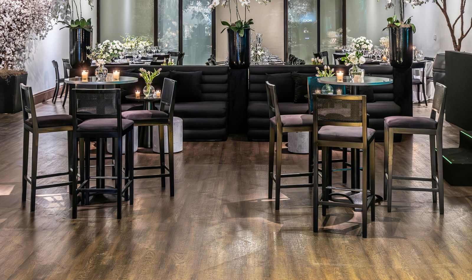 Brightly lit indoor event space with small tables, chairs, and floral decorations.