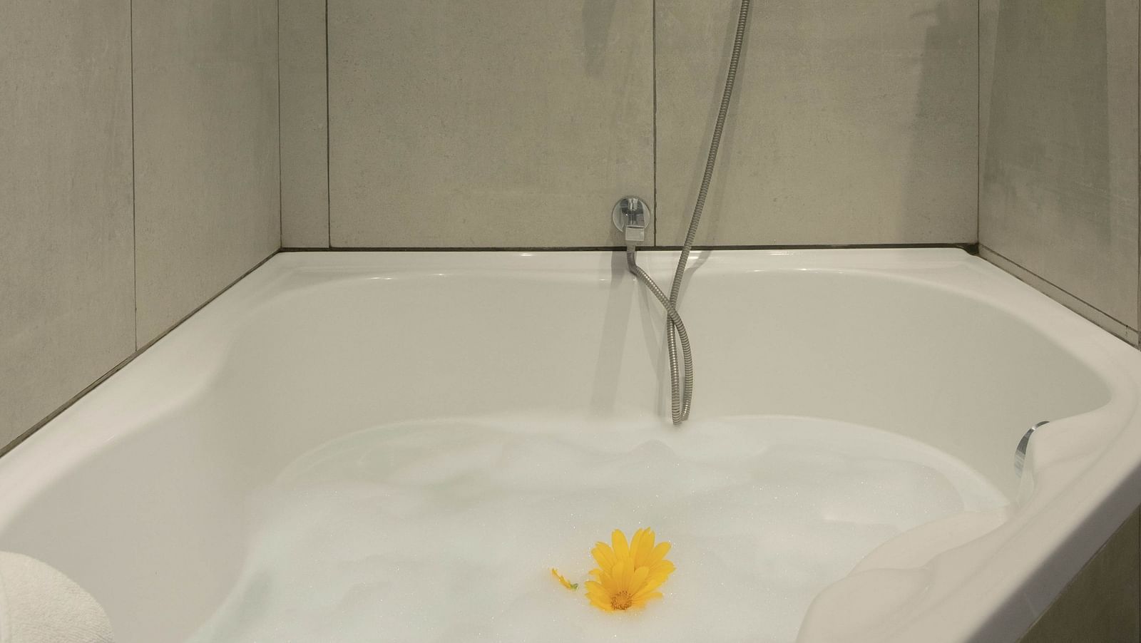 Image of a bathub at Coral Suite at Coral Reef Hotel and Spa in Port Blair with a little yellow flower soaked in water and foam