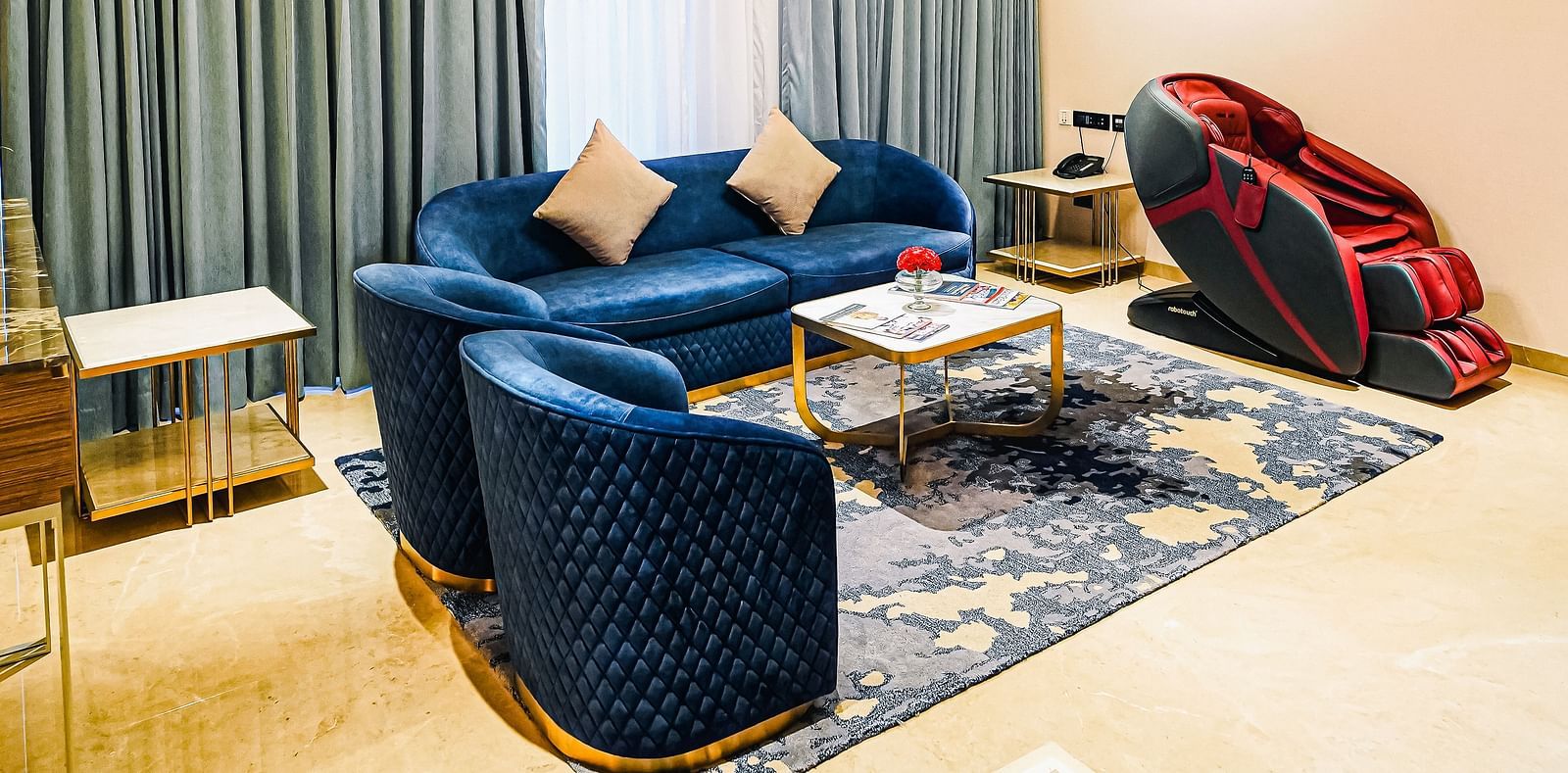 An image of Grand Velammal Suite with a blue couch and a massage chair