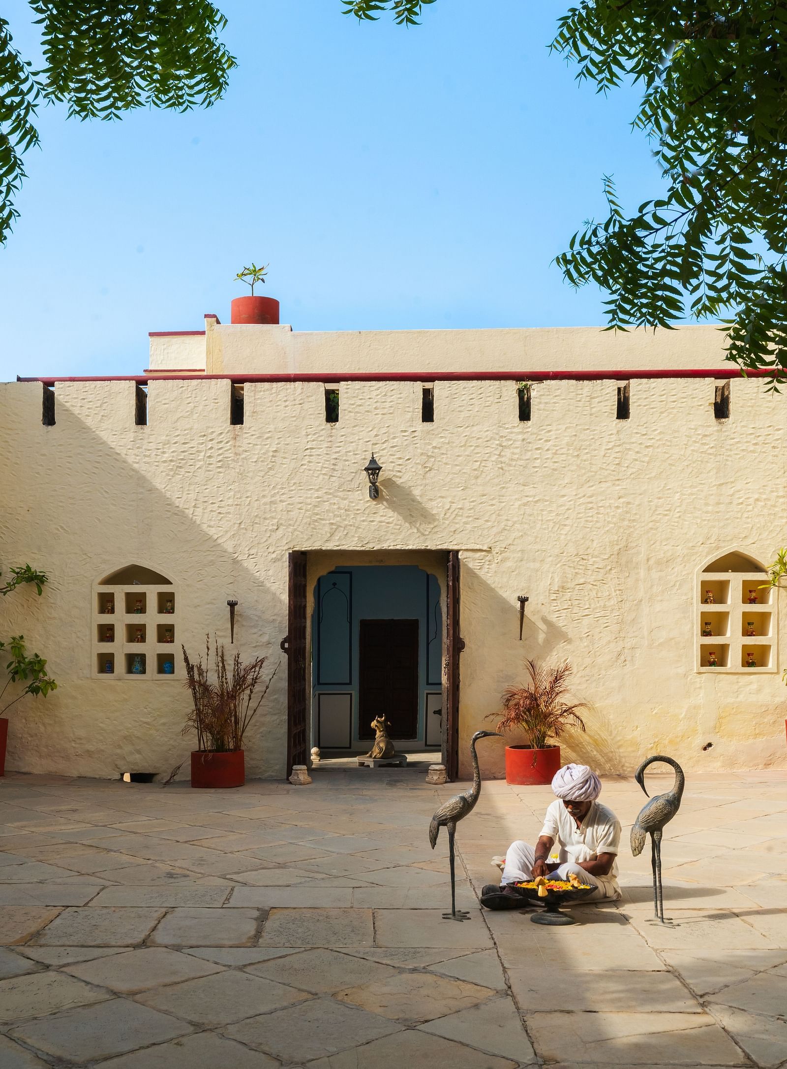 A person plays a stringed instrument in a courtyard outside a building at Fort Barli, Ajmer.