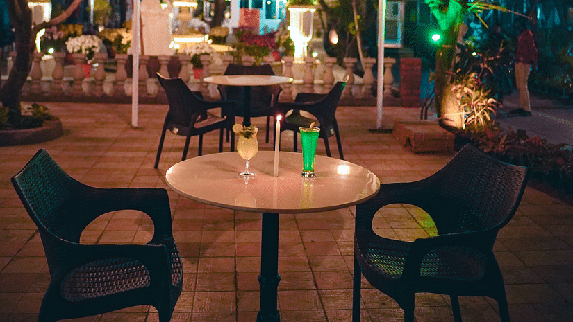 An image of outdoor garden featuring table and chairs surrounded by trees and lamp shades - Rangamati Garden Resort