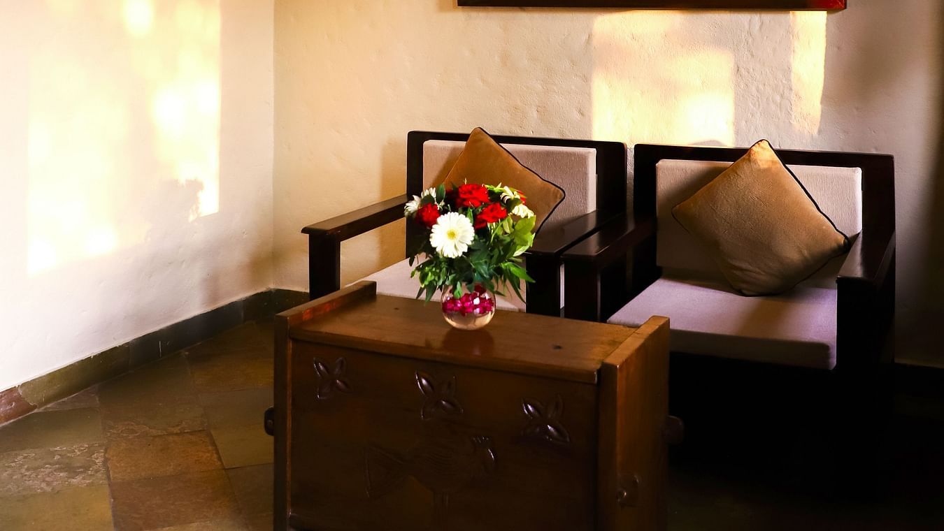 Two chairs and a teapoy rest beneath a portrait on the wall
