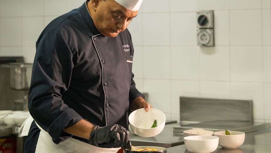 A chef standing near the kitchen counter, working on his dish at Ananta Spa and Resort, Ajabgarh