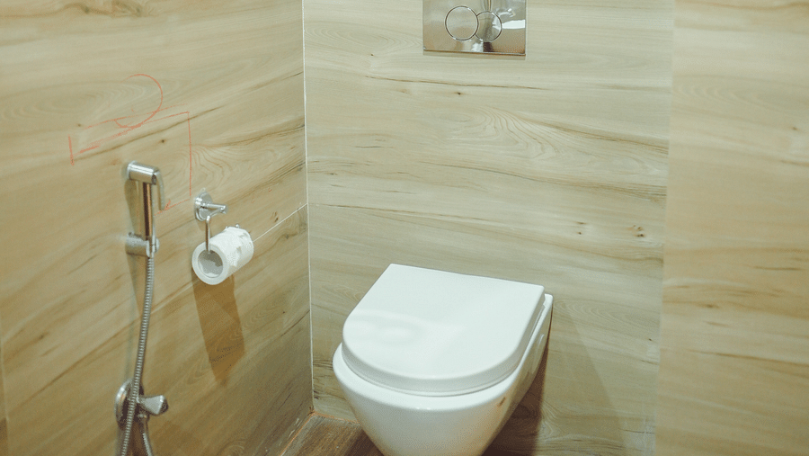 image of a bathroom featuring a commode and shiny bathroom faucets