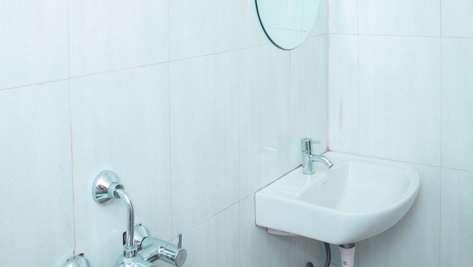 image of a bright bathroom featuring a wash basin along with a circular mirror above it