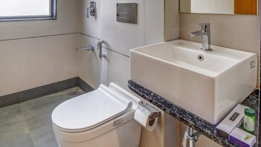 Modern bathroom with toilet, washbasin, mirror, and shower area at VITS Select Nashik Hotels & Resorts.