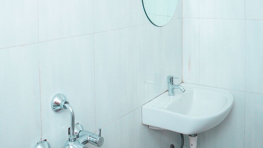 image of a bright bathroom featuring a wash basin along with a circular mirror above it