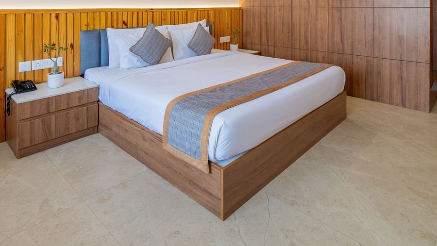 Deluxe room with wooden interiors, a king size bed, and a ceiling fan at Hotel Highway King, Bagru