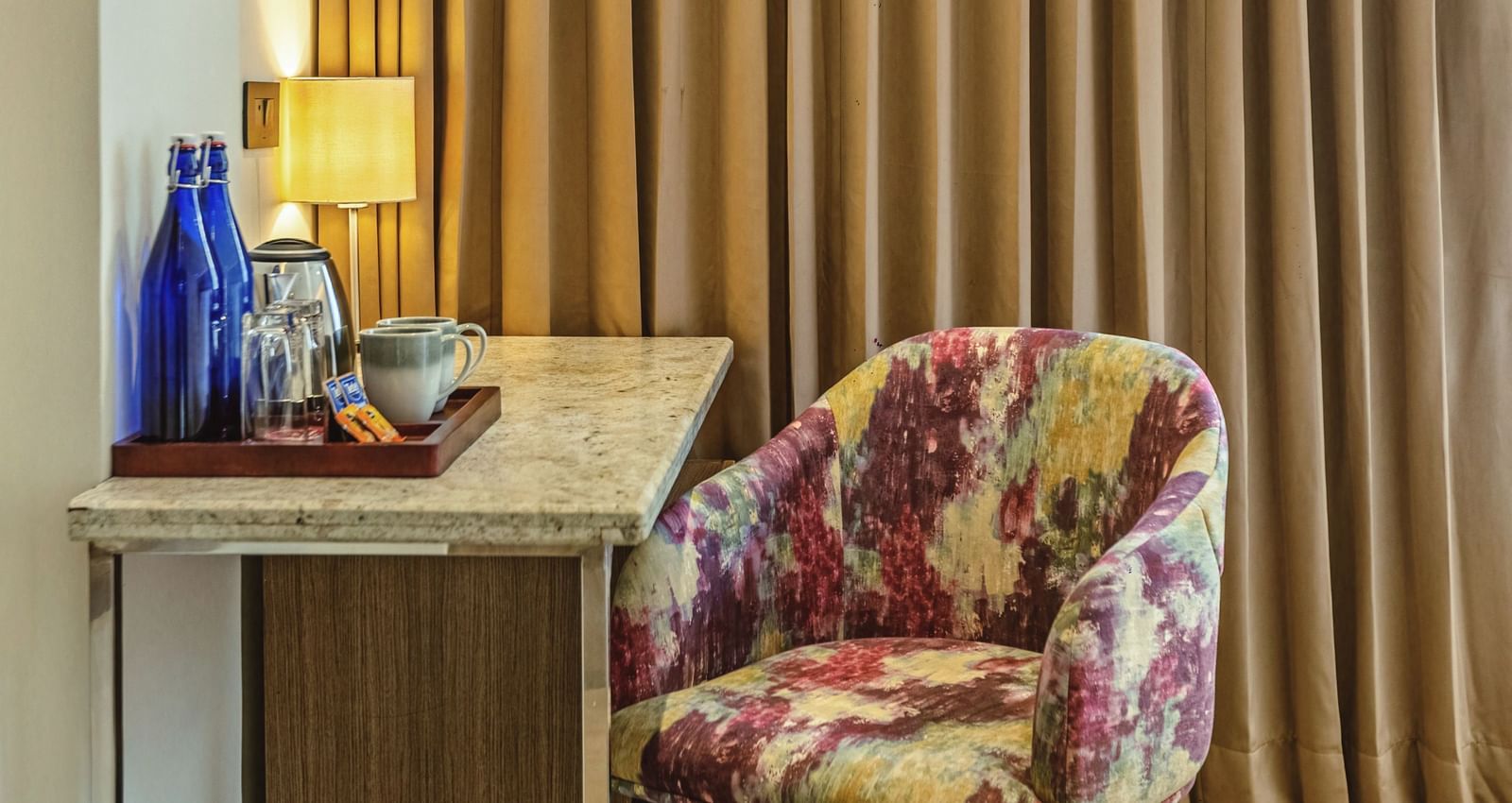 A close-up of a desk with a chair in a room at Mango Hill Central, Chennai. Gold curtains hang behind the desk.