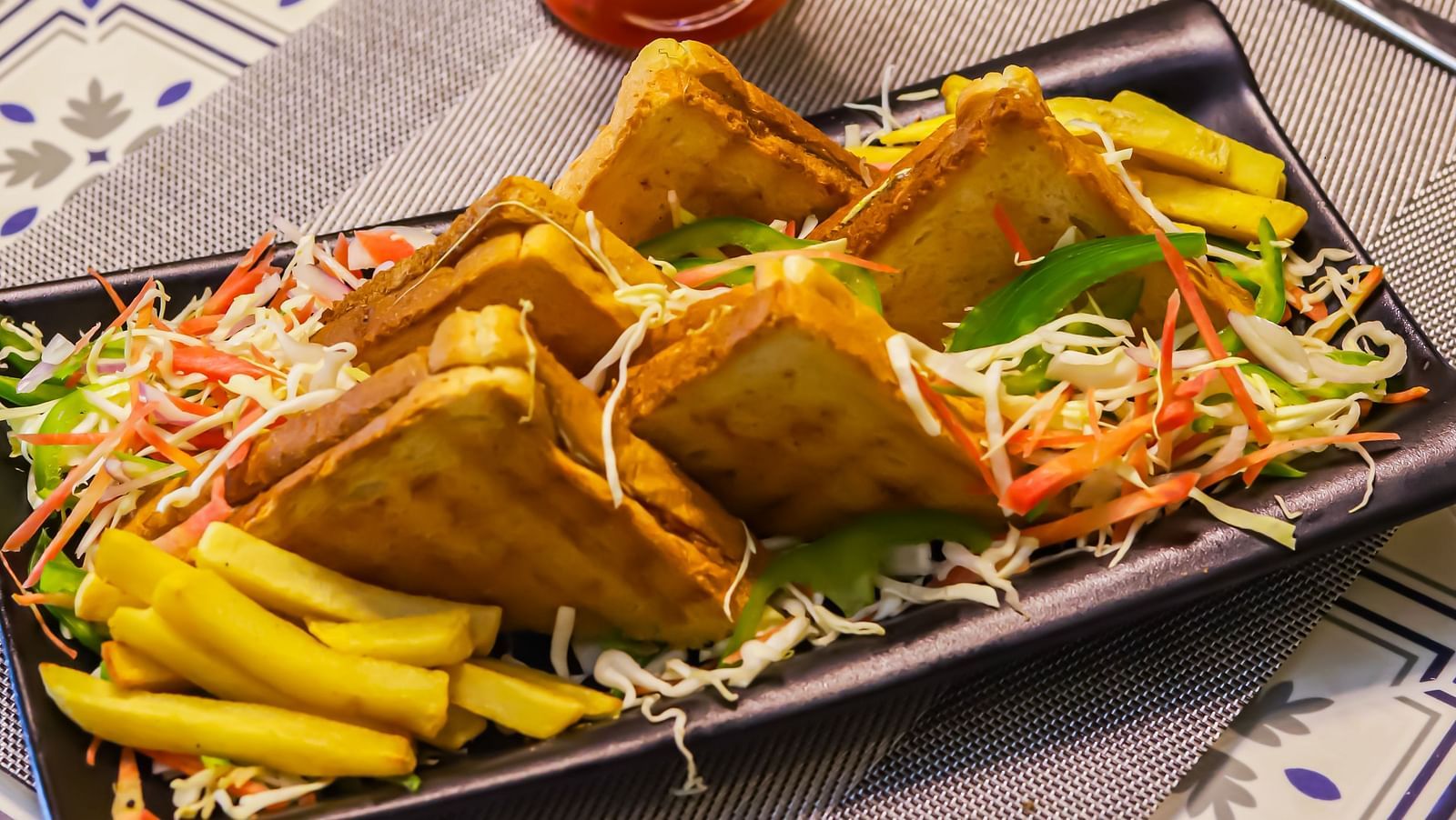 A tray with fried food and a tall glass of drink are on a table with a patterned cloth at Vedikant Resorts The Mallard Corbett.