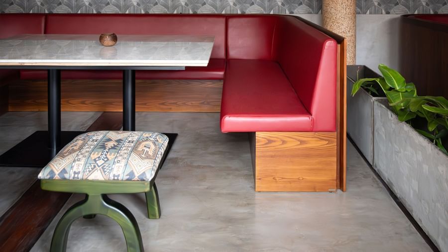  A vibrant dining area at Shilton International, Kochi, with patterned wallpaper, built-in seating, and modern decor.