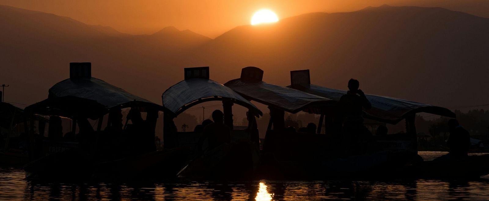 Scenic sunset over a tranquil lake with silhouetted houseboats.