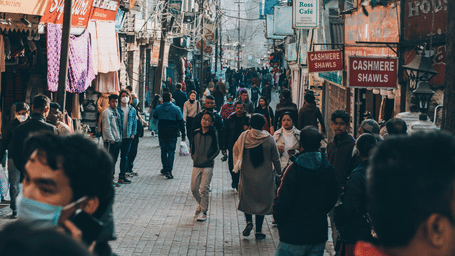 A busy street scene with numerous pedestrians and various buildings lining both sides of the road.