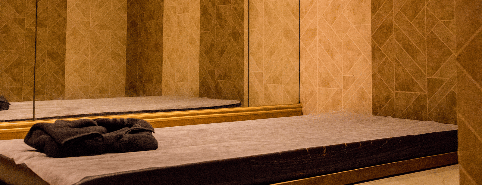 A mattress kept on the floor of a dimly lit room with a wall attached with full length mirror at Benzz Park, Vellore.