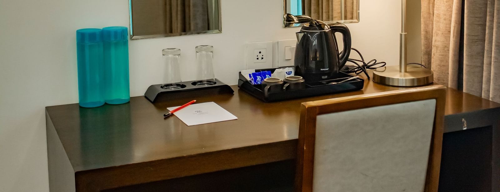 A workstation with a table lamp, socket, and an electric kettle kept on a tray at The Hamuse Hotel, Kodaikanal