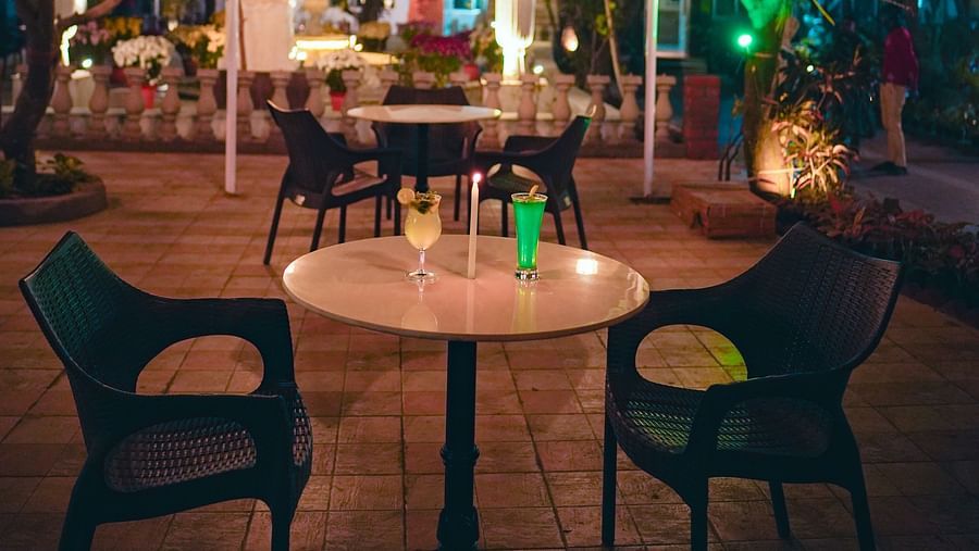 An image of outdoor garden featuring table and chairs surrounded by trees and lamp shades - Rangamati Garden Resort