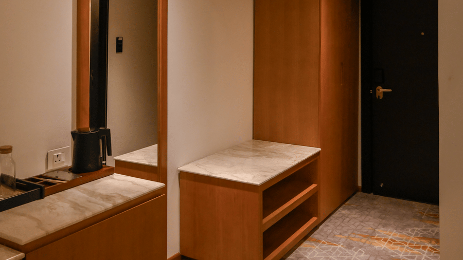 An entryway hallway showing a wooden wardrobe, a luggage rack, and a full-length mirror on the wall at Tiara by MPS.