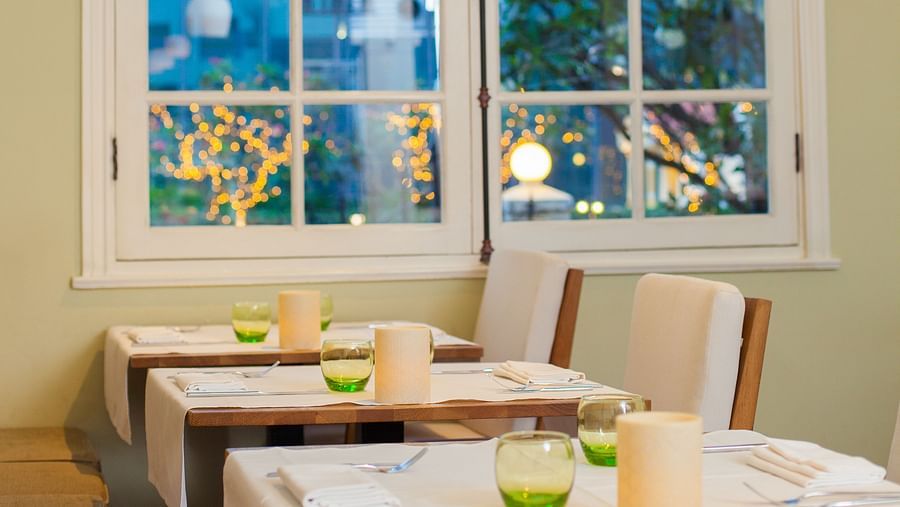 A dining area with a table and chairs next to a window with a view of the outdoors | The Shop | Central Mansions, Phnom Penh