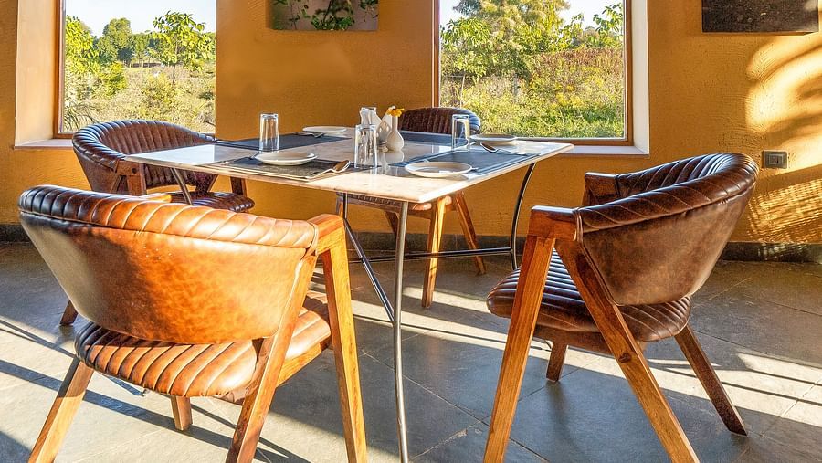 An image of L cave restaurant with tables and chairs in boho theme where sunlight is seeping in and there are two open entrances - Kurja Jawai
